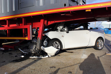 A car that has crashed into a lorry trailer causing much damage
