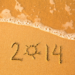 2014 written in sand on beach texture - soft wave of the sea.