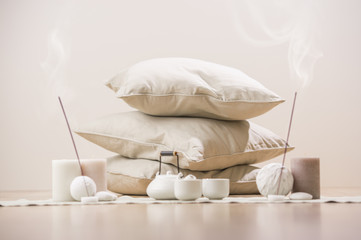 Teapot and cups with aromatic sticks and candles in front of pil