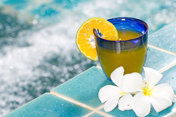 orange cocktail in blue glass by Jacuzzi pool