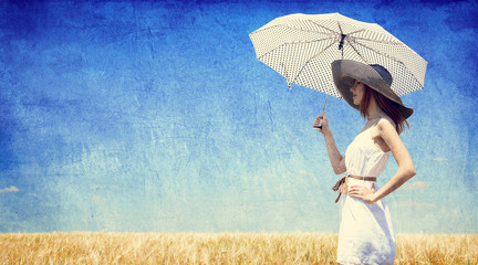 Women with umbrella at wheat field.