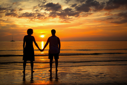 Romantic picture: Silhouettes young couple on the beach.
