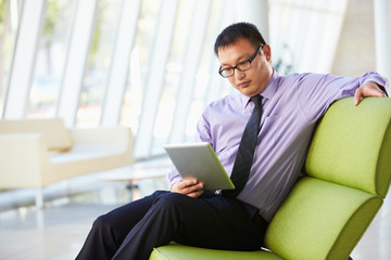 Businessman Sitting In Modern Office Using Digital Tablet