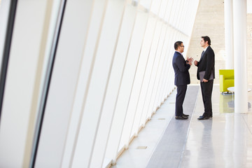 Two Businessmen Having Informal Meeting In Modern Office