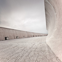 Concrete dike or dam structure, wall and floor, cloudy sky.