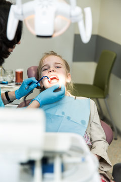 Photo of a little girl during the drilling of the tooth