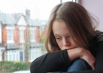 A young girl sad on her window close to tears