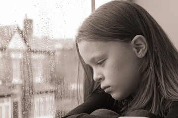 Beautiful young girl looking emptily out of the window