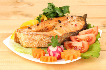 Appetizing grilled salmon with vegetables on wooden table