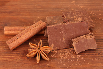 Chopped chocolate with cocoa, spices, on wooden background