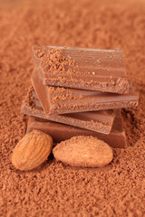 Chopped chocolate with cocoa, on brown background