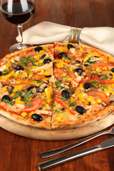Tasty pizza with wine on wooden table close-up