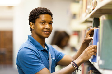 young male african uni student looking for books in library