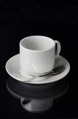 Empty white cup and saucer on a black background