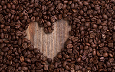 Heart shape made from coffee beans on wooden table