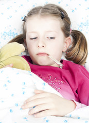 Sick girl with a thermometer and teddy bear lying in bed