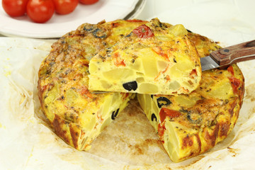 Spanish potato tortilla with black olives and tomatoes
