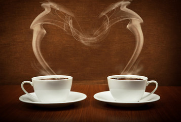 Heart shape by steaming cups of coffee