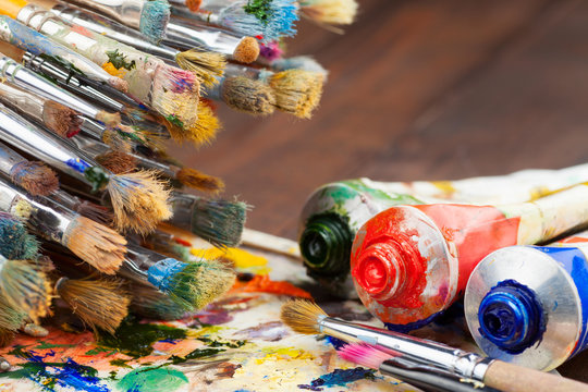 art brushes, oil paint tubes, artist palette on wooden table
