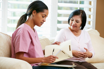 Obraz premium Nurse Discussing Records With Senior Female Patient at Home