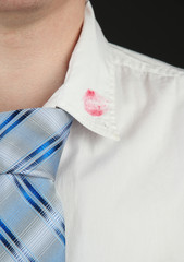 Lipstick kiss on shirt collar of man, isolated on black