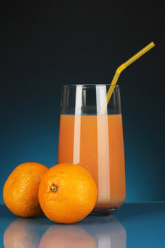 Delicious tangerine juice in glass and mandarins next to it