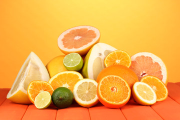 Lots ripe citrus on wooden table on orange background
