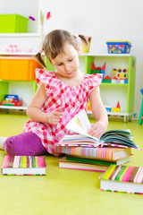 Fototapeta premium Little girl reading book on floor