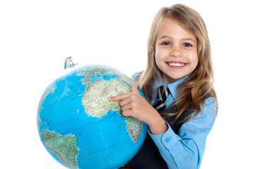 Pretty school child holding globe and pointing