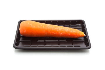 Single carrot on black plastic tray, isolated on white backgroun