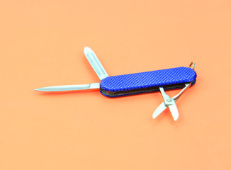 Blue small Swiss knife on orange background