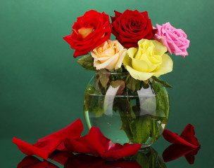 Beautiful roses in glass vase on green background
