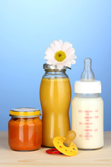Baby food, bottle of milk, puree and juice on blue background