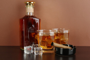 Bottle and Glasses of whiskey and cigar on brown background