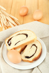 Loaf with poppy seeds on color plate, on wooden background