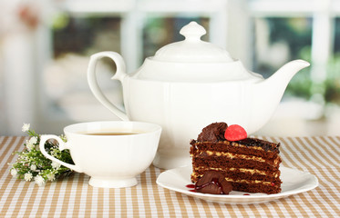 Teapot, cup of tea and delicious cake on window background