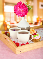 Cups of tea with flower and cakes