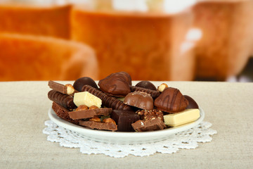 Chocolate and sweets on white plate, on bright background
