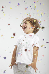 Smiling child with rimmed glasses and confetti