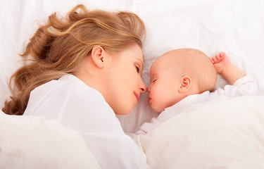 sleeping together. mother embraces the newborn baby in bed