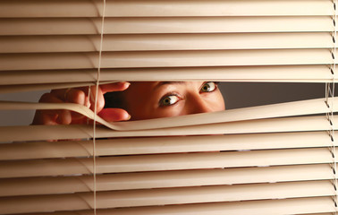 Portrait of a woman looking through out the blinds