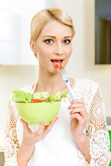 Portrait of a beautiful young woman eating vegetable salad