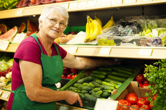 Senior woman arranging vegetables on shelf