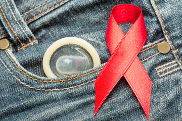 Condom peeking out from pocket with red awareness ribbon