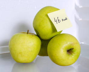 Apples with marked calories on fridge shelf