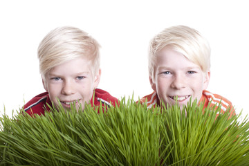 Zwei Kinder hinter Grasbüscheln - Zwillinge
