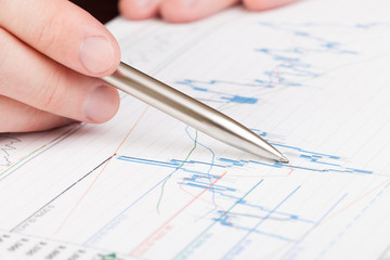 Businessman indicating with pen on diagram of financial report