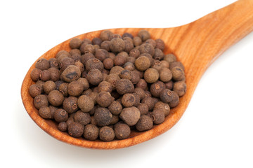 allspice in a  wooden spoon