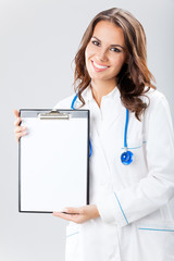 Female doctor showing blank clipboard, on grey