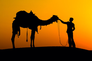 Silhouette man and camel at sunset, India